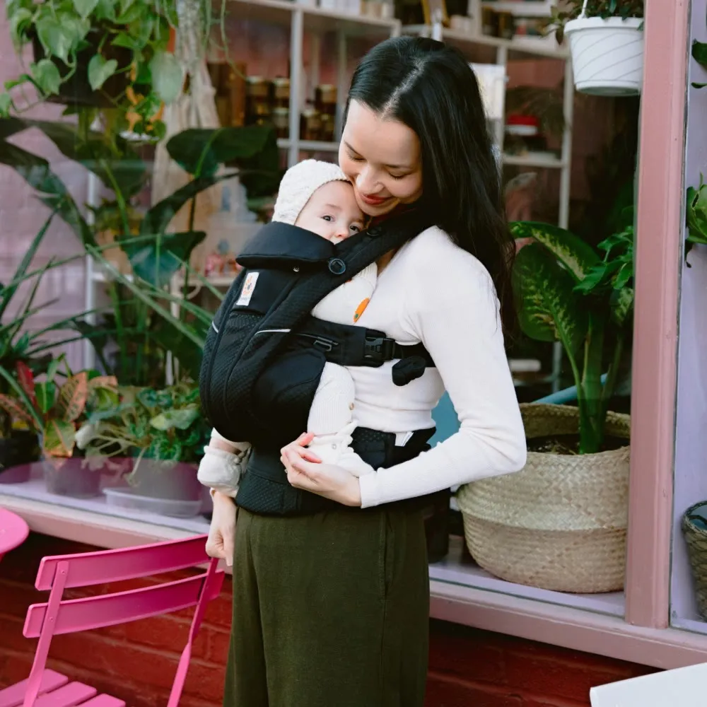 A parent carrying their baby in an Ergobaby carrier.